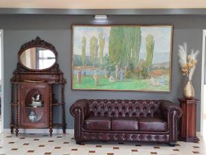 a living room with a brown leather couch and a mirror at Penelope Apartment Hotel in Dassia