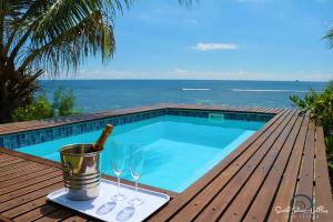 a bottle of champagne and wine glasses next to a swimming pool at South Point Villas Cerf Island in Cerf Island