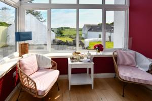 two chairs and a table in a room with a window at High Clachan Farmhouse in Stranraer