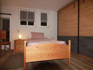 a bedroom with a bed with a wooden frame and windows at Stadthaus in Mellrichstadt