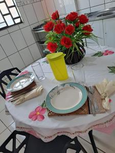 a table with a plate and a vase of red flowers at João eudes Rodrigues de Souza in Marabá