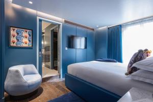 ein blaues Schlafzimmer mit einem Bett und einem Stuhl in der Unterkunft Sun Street Hotel Shoreditch in London