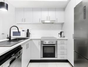 a kitchen with white cabinets and a stainless steel refrigerator at Broadwater Parklands Paradise in Gold Coast