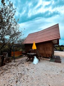 Cabaña de madera con mesa y sombrilla amarilla en Koča Janka in Metke en Velika Loka