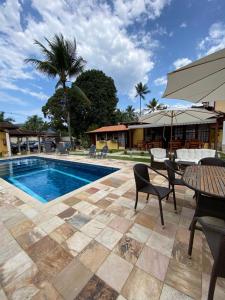 una piscina con sillas, una mesa y un patio en Pousada Antígona, en Paraty