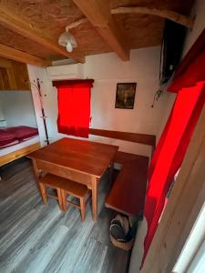a small room with a wooden table and red curtains at Koča Janka in Metke in Velika Loka