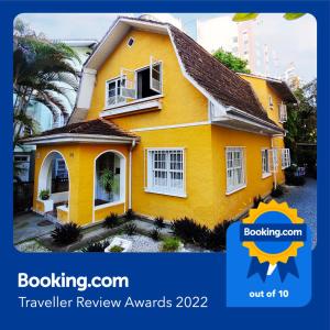una casa amarilla con las palabras premios de revisión del viajero boatingcon en Casa Amarela Blumenau Hospedagem Alternativa en Blumenau