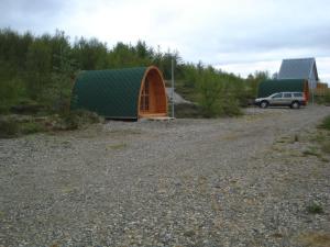 a building with a green roof on a gravel road at Vinland Camping Pods in Egilsstadir