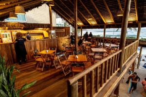 um restaurante com mesas e cadeiras de madeira num piso de madeira em Longboard Paradise Suítes no Rio de Janeiro