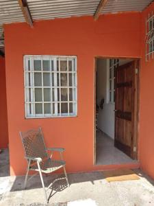 uma cadeira sentada do lado de fora de uma casa com uma parede laranja em Cozy 1 br 1 bath apartment with free parking em Penonomé