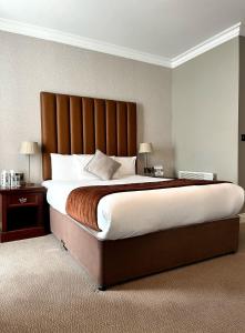 a bedroom with a large bed with a wooden headboard at The Western Hotel in Galway