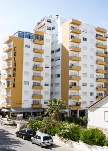 a large apartment building with cars parked in a parking lot at Columbia Apartamentos Turisticos in Portimão