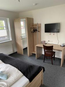 een slaapkamer met een bureau, een bed en een televisie bij Hotel Zum Großen Krug in Wirdum
