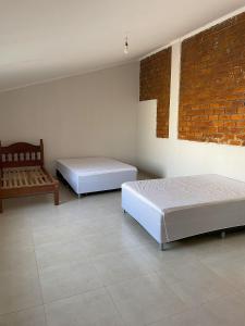 a bedroom with two beds and a brick wall at Casa com Piscina em Três Ranchos in Três Ranchos