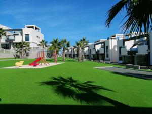 un patio con parque infantil frente a un edificio en Oasis Beach VIII Punta Prima 3023, en Torrevieja