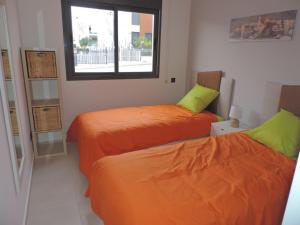 Duas camas com lençóis laranja num quarto com uma janela em Oasis Beach VIII Punta Prima 3023 em Torrevieja