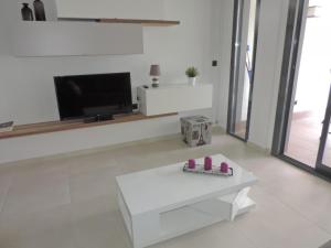 uma sala de estar com uma mesa branca e uma televisão em Oasis Beach VIII Punta Prima 3023 em Torrevieja