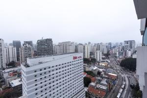 uma vista para uma cidade com um edifício branco alto em Vista Alta-23ºandar/Academia/Insper e Hosp.São Luiz 650mts/Pq.Ibirapuera 1Km/ WiFi 257Mbps em São Paulo