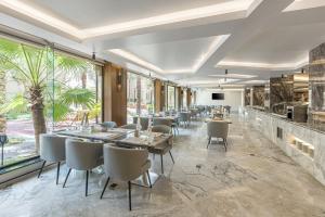 Madareem Hotel في الرياض: مطعم بطاولات وكراسي ونافذة كبيرة