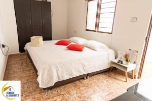 a bedroom with a bed with red pillows on it at KOMODO ALOJAMIENTO- hostal autoservicio - ubicado muy cerca al centro histórico -Habitaciones con baño privado, wifi , cama 2x2 in Popayan