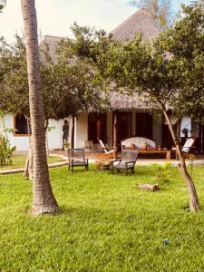 ein Haus mit zwei Stühlen in einem Garten mit Bäumen in der Unterkunft Malindivillabaobab in Malindi