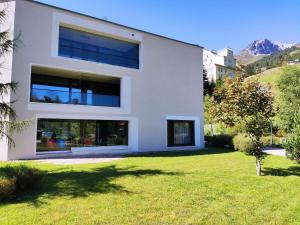 ein weißes Haus mit Rasen davor in der Unterkunft Apartment Seewiesenstrasse by Interhome in Davos