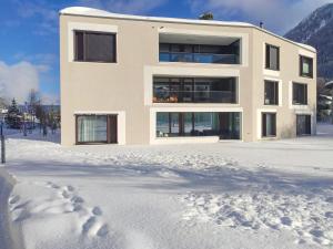 une maison dans la neige avec des empreintes de pied dans la neige dans l'établissement Apartment Seewiesenstrasse by Interhome, à Davos