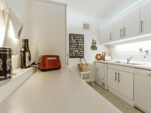 una cocina con armarios blancos y una maleta roja en la encimera en Apartment Tauernspirit by Interhome en Bad Gastein