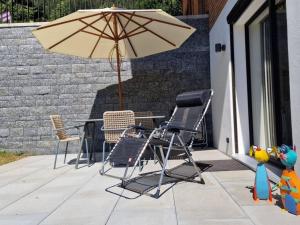 einen Tisch, Stühle und einen Regenschirm auf einer Terrasse in der Unterkunft Apartment Gletscherhorn Sockelgeschoss Südwest by Interhome in Zweisimmen