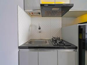 a small kitchen with a sink and a stove at OYO Life 92649 Jarrdin Apartment By Glory in Bandung