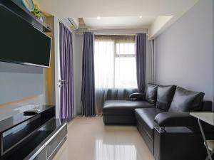 a living room with a black couch and a tv at OYO Life 92649 Jarrdin Apartment By Glory in Bandung
