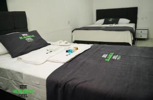 two beds in a hotel room with black and white sheets at Blaundus Otel in Uşak