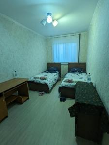 een kamer met 2 bedden, een tafel en een bureau bij Apartament motel in Chişinău