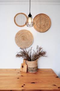 a table with rattan baskets on a wall and a lamp at Shilo Beach Home - Loadshedding Free in Wilderness