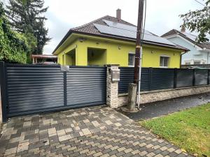 a black fence in front of a yellow house at Star Street Home in Mosonmagyaróvár