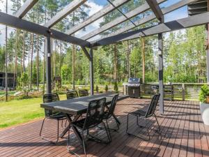 een houten terras met een tafel en stoelen en een grill bij Holiday Home Villa murdoc by Interhome in Vierumäki