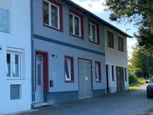 a white building with red windows and a car parked in front at Haus 77 in Hollabrunn