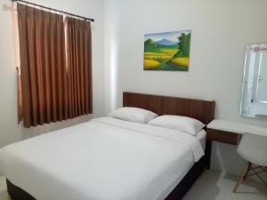 1 Schlafzimmer mit 2 Betten, einem Schreibtisch und einem Fenster in der Unterkunft Omah Bondi Family Homestay by FH Stay in Yogyakarta