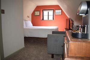 ein Schlafzimmer mit einer orangefarbenen Wand und einem Bett in der Unterkunft Alma Inn & Dining Rooms in Harwich