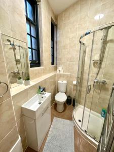 uma casa de banho com um WC, um chuveiro e um lavatório. em Modern 1-Bedroom Apartments in Shoreditch, Old Street em Londres