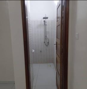 a bathroom with a shower and a white tile floor at Salam in Saint-Louis