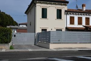 une maison blanche avec une clôture devant elle dans l'établissement Garofoli Apartments, à San Giovanni Lupatoto