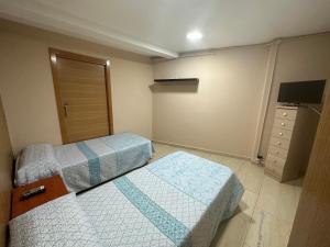 1 dormitorio con 2 camas y TV. en Hostal El Gaitero, en Arroyomolinos