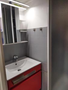 een badkamer met een witte wastafel en een rode kast bij Superdévoluy Les Issarts in Superdevoluy