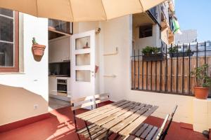una panca di legno seduta su un balcone con ombrellone di Gracia15 a Barcellona