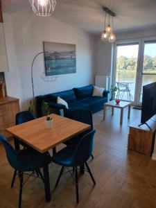 sala de estar con mesa y sofá azul en Apartament z pięknym widokiem en Nowy Dwór Mazowiecki