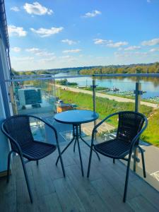 two chairs and a table on a balcony with a view of a lake at Apartament z pięknym widokiem in Nowy Dwór Mazowiecki
