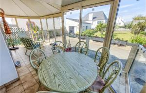 - une table et des chaises sur une terrasse couverte avec moustiquaire offrant une vue sur une maison dans l'établissement Pet Friendly Home In Plogoff With Kitchen, à Plogoff