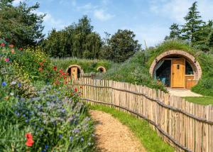 um jardim com uma cerca de madeira e um edifício com um telhado de relva em Luckington Burrows em Frome