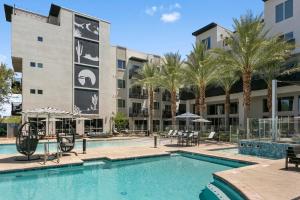 a swimming pool with tables and chairs in front of a building at Premium One and Two Bedroom Apartments at Slate Scottsdale in Phoenix Arizona in Scottsdale